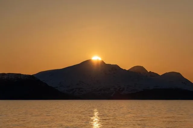 The midnight sun over the island of Reinøya in the Ullsfjord in Norway