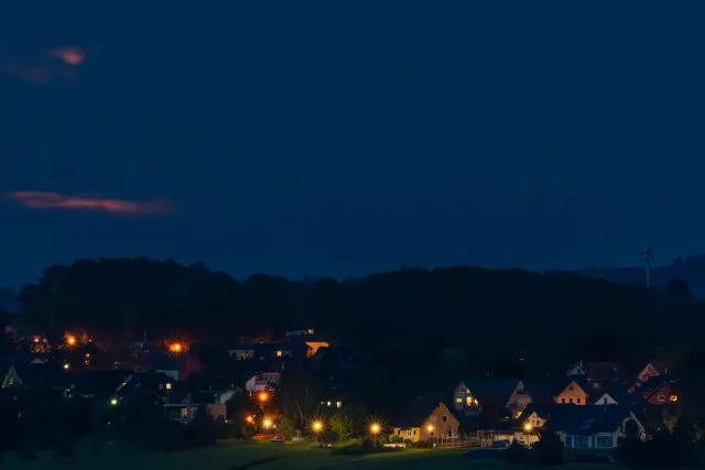 Super moon as a blue moon behind clouds over Lichtenberg in Hennef